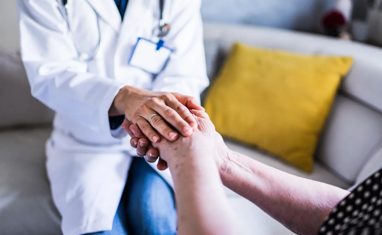 compassionate primary care visit holding senior patient hands